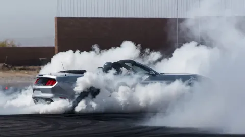 Ford Mustang burnout creating tire smoke, illustrating accelerated tire wear and tire replacement in Arizona's extreme heat.