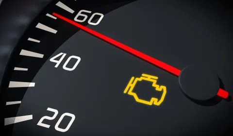 Illuminated check engine warning light on a vehicle dashboard indicating a possible engine or emissions system problem.