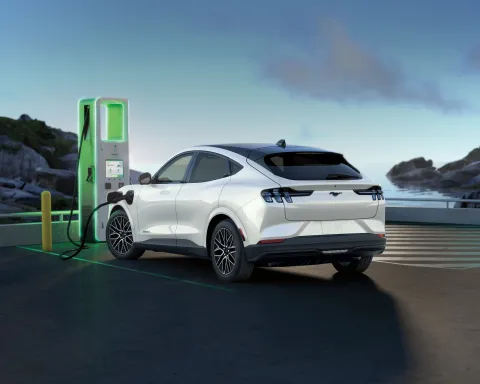 White Ford Mustang Mach-E charging at an EV charging station, illustrating electric vehicle maintenance and battery care in Arizona.