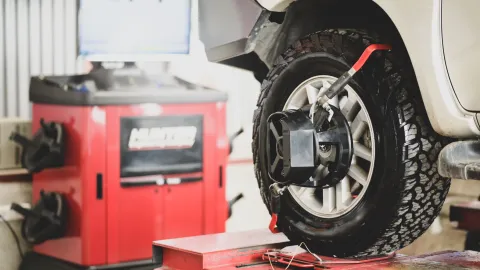 Wheel alignment equipment attached to a vehicle tire during a wheel alignment inspection at an automotive repair shop.